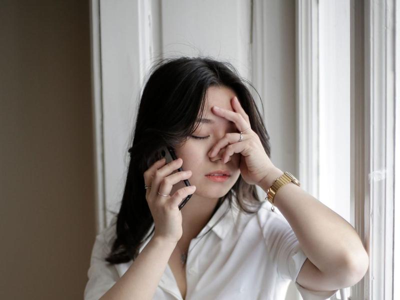 Une professionnelle au téléphone, la main sur le visage, débordée.